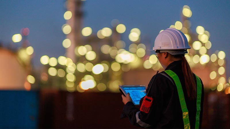 A person in hardhat and safety vest holding a tablet