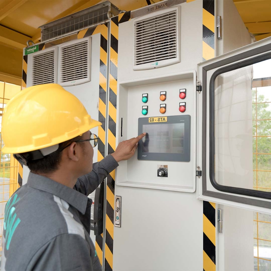 A person wearing a hard hat and pointing at a machine