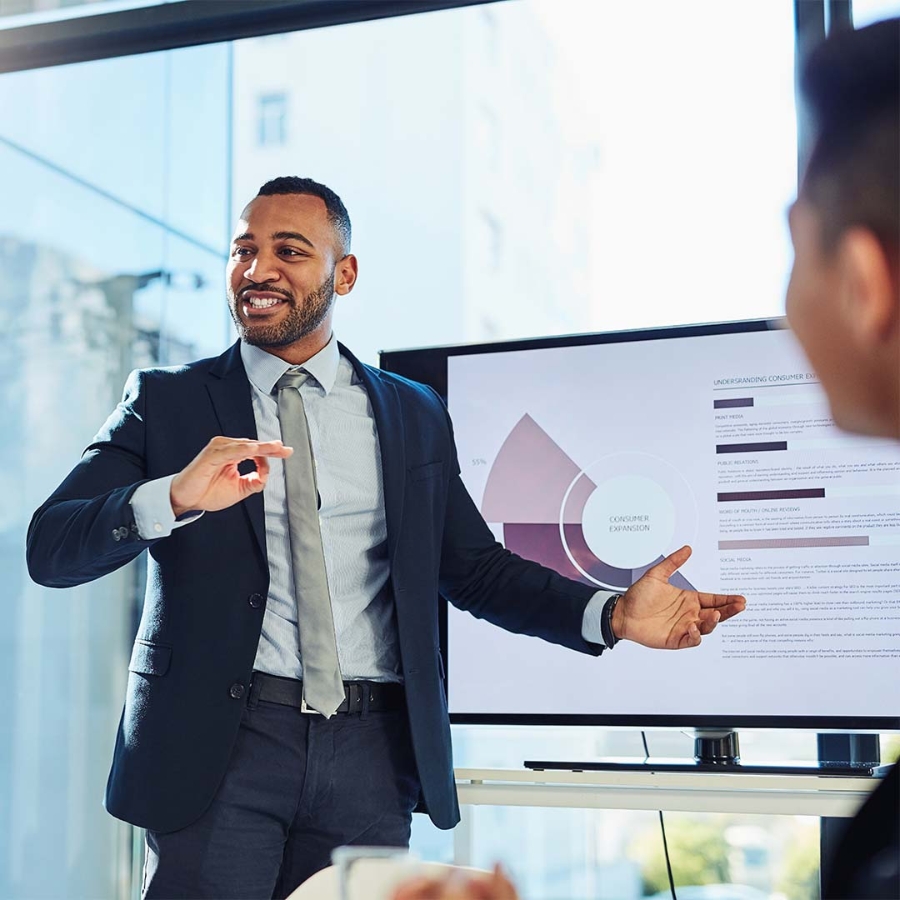 A person in a suit pointing at a screen