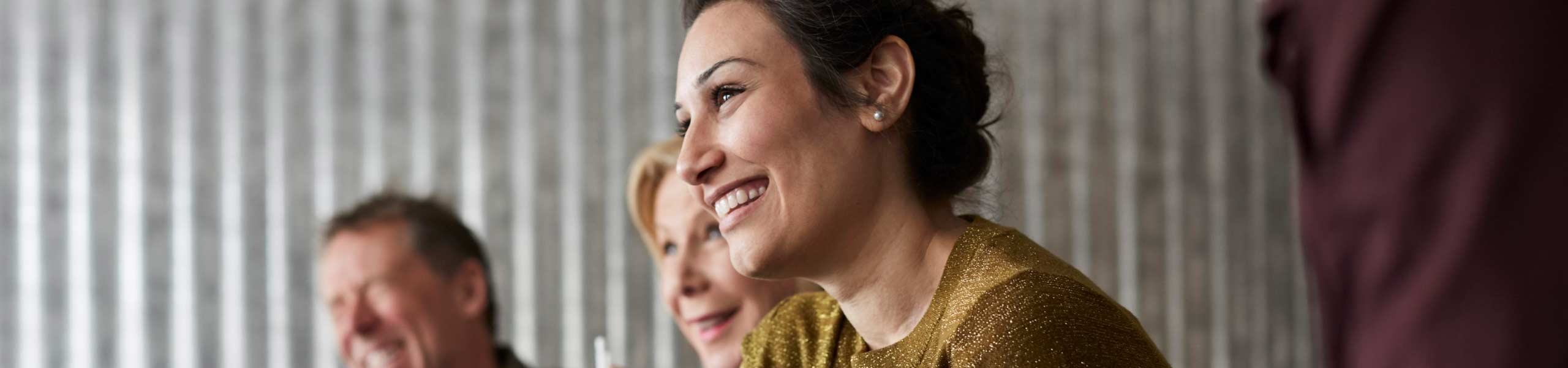 Cheerful creative business colleagues sitting at conference table while looking away in board room