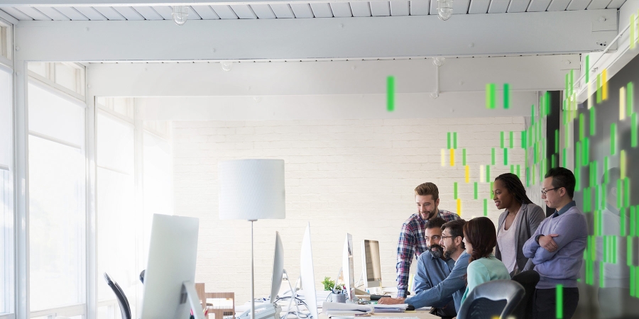 people in office standing around a computer