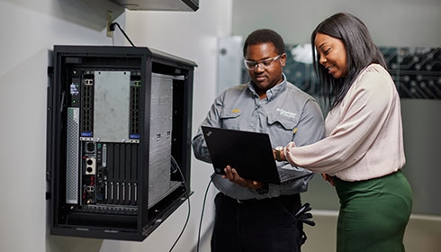 An end user consulting their UPS status with a Schneider Electric Field Services representative