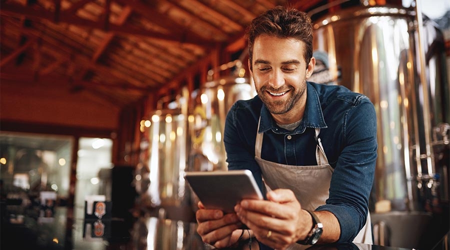 A person in an apron looking at a tablet