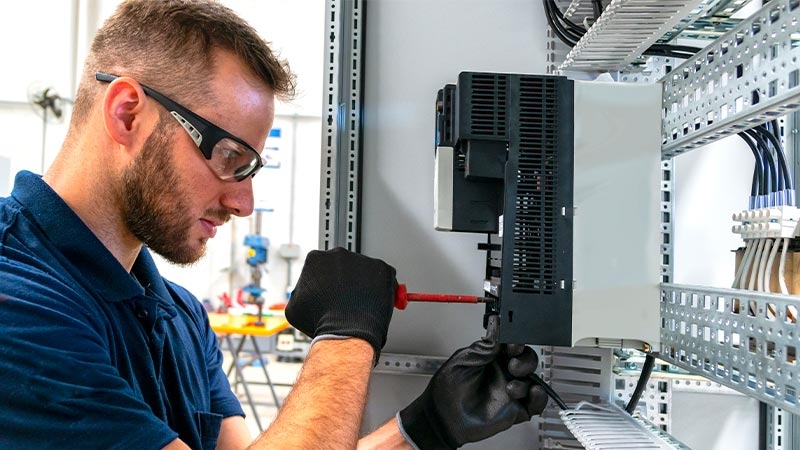 A person wearing safety glasses and gloves working on a machine