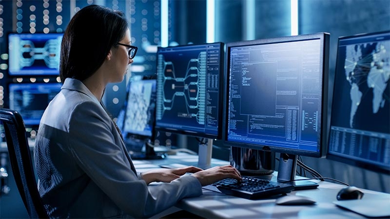 A person sitting at a desk with multiple computer screens