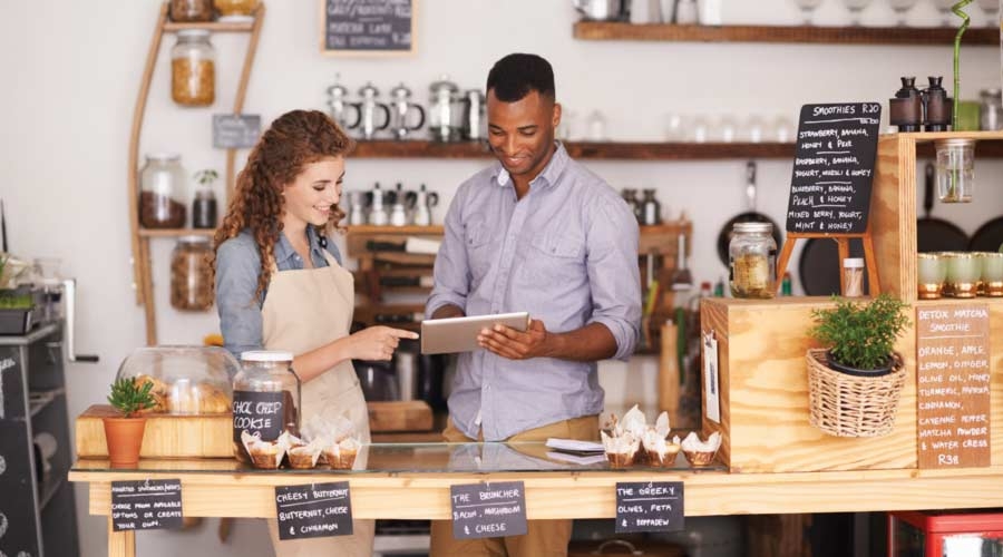 Cropped shop of a handsome coffee shop owner showing a waitress the ropes