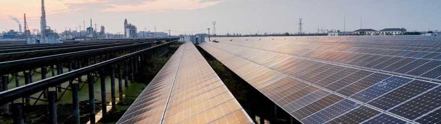 Solar power plant with chemical plant background at sunset