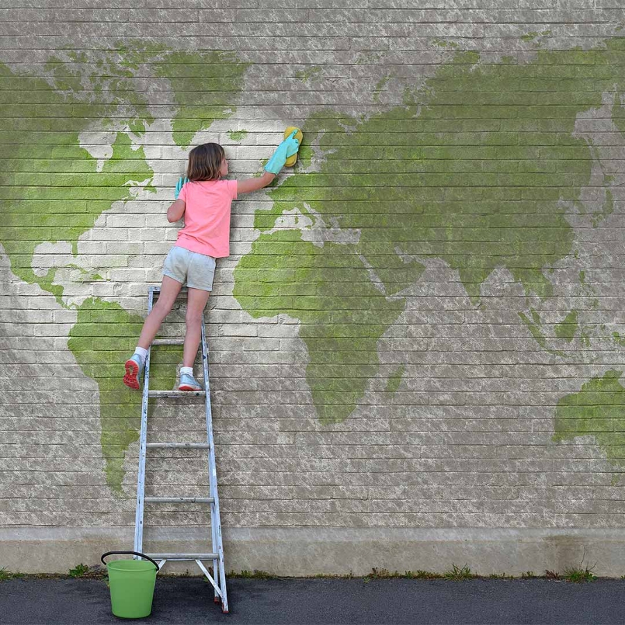 A child on a ladder painting a wall with a map of the world