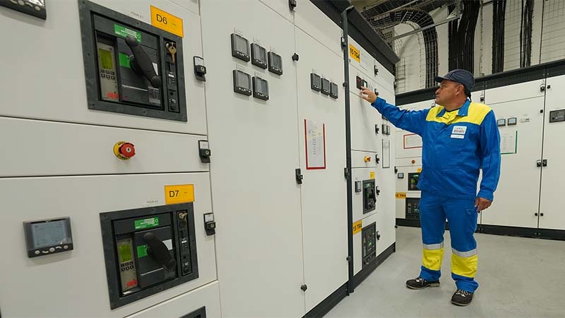 A person in a blue uniform standing next to a large white machine