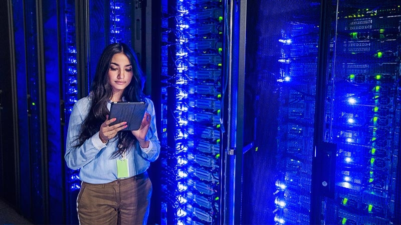 A person holding a tablet in front of a server room