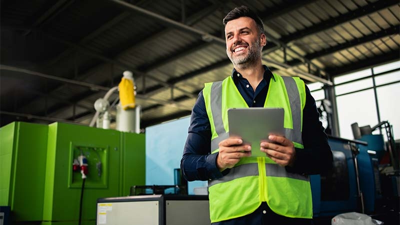 A person in a safety vest holding a tablet