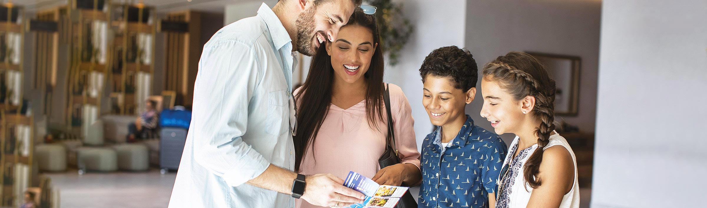 Familj med två barn som står i rum och tittar i broschyr