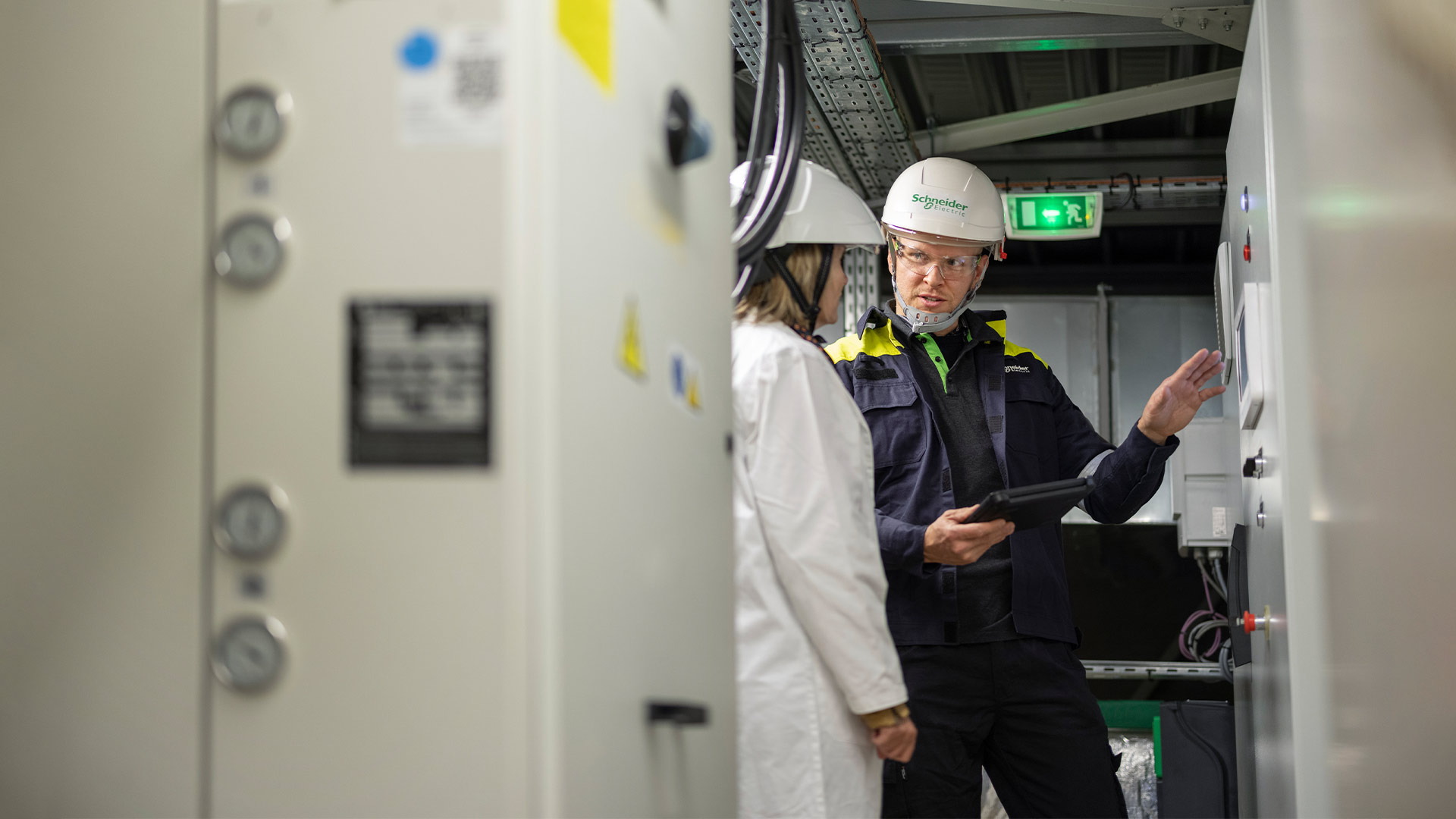 Men with hard hats talking in front of a control panel