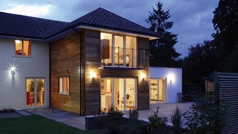Residence in white and wood at night with all lights turned on.