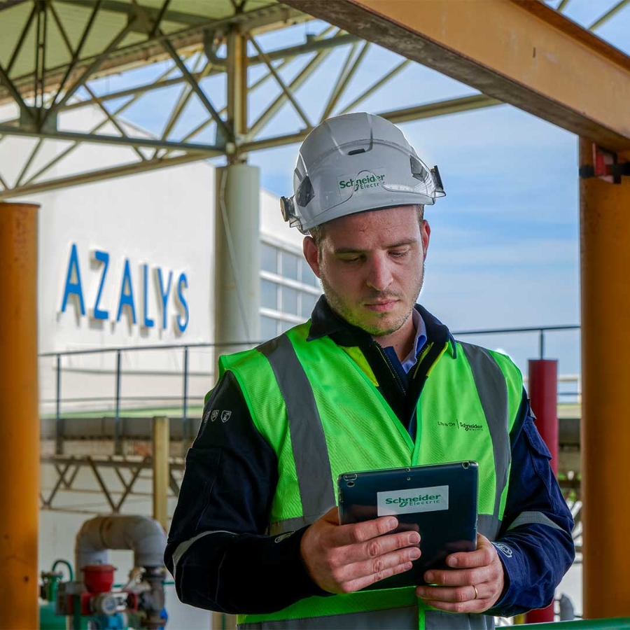 A person in a safety vest and hard hat looking at a tablet