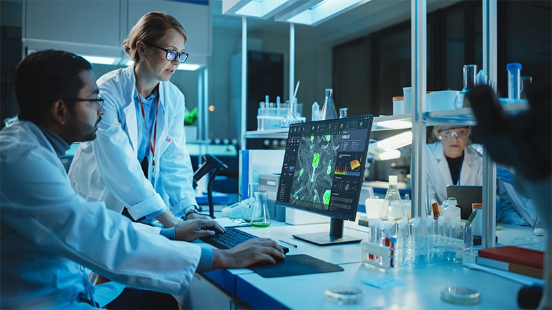 A person in a lab coat looking at a computer