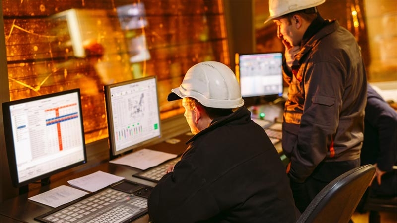 A group of men in hard hats looking at computers