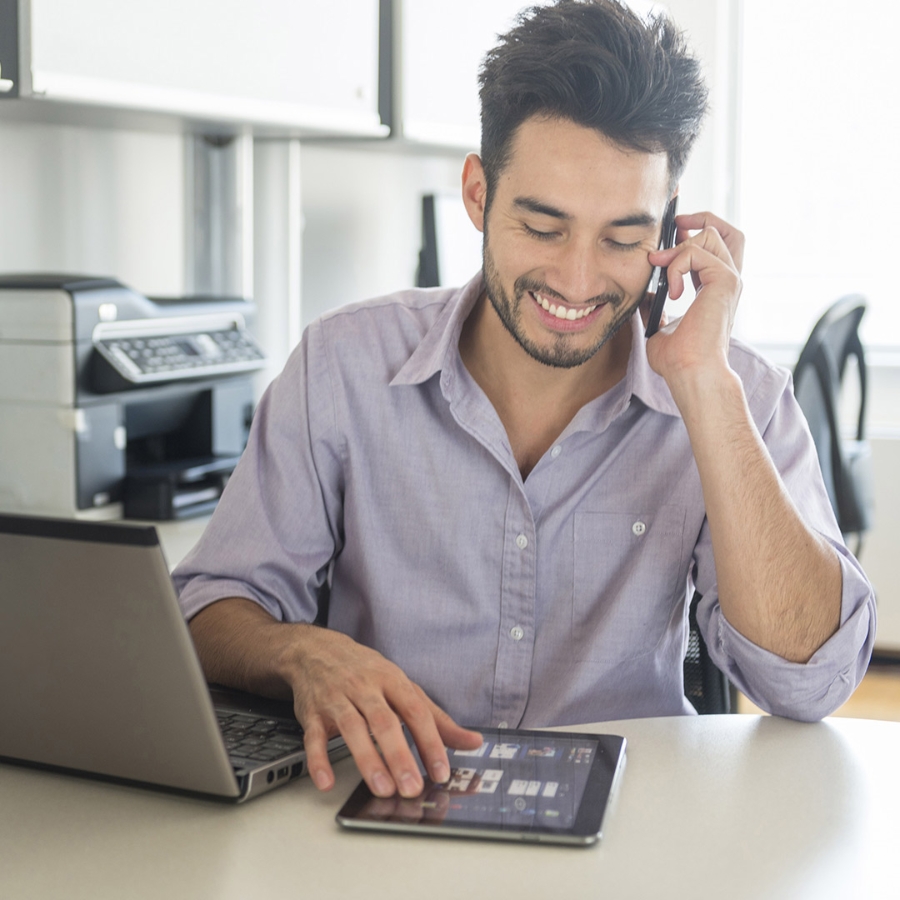 man talking on a mobile phone while using a digital tablet