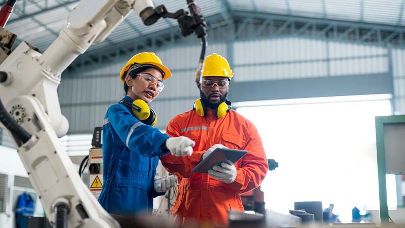 Female Quality Engineer and Male Production Engineer talking at welding robot in a factory