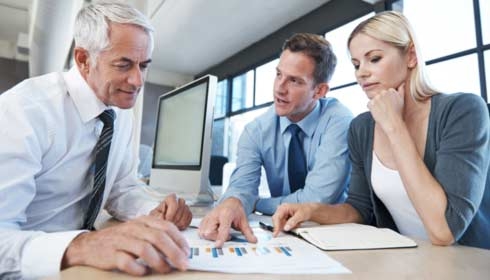 Three business people discussing test results next to a computer