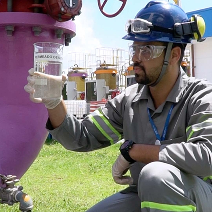 A person wearing a hard hat and holding a plastic container