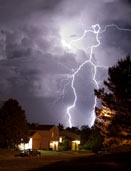 Lightning bolt and thunderhead storms over neighborhood homes