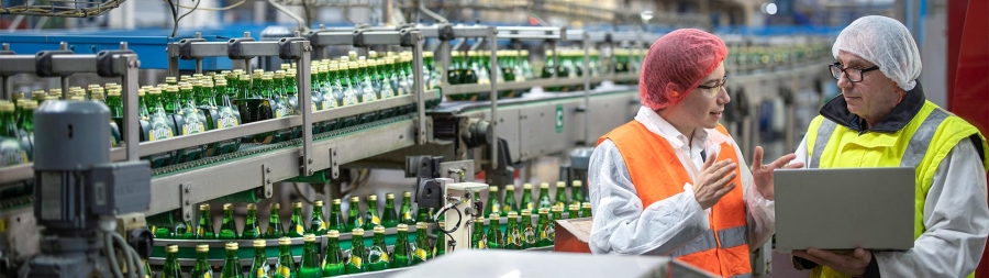 two workers in a bottle assembly working on laptop