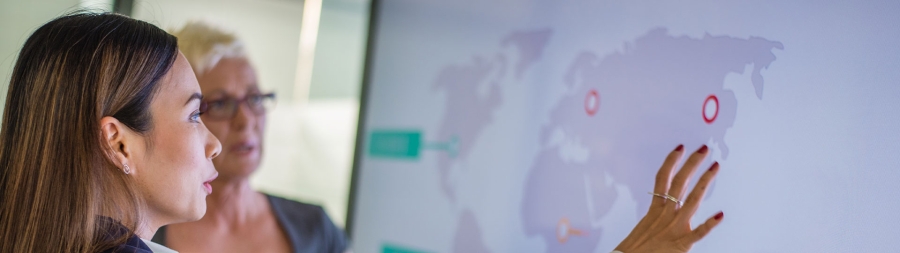 White businesswoman at whiteboard leading meeting in office and showing graph.