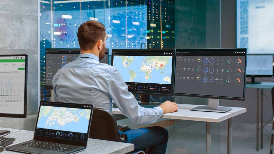 A person sitting at a desk with multiple computer screens