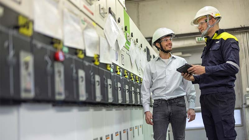 A person wearing a white helmet and holding a tablet