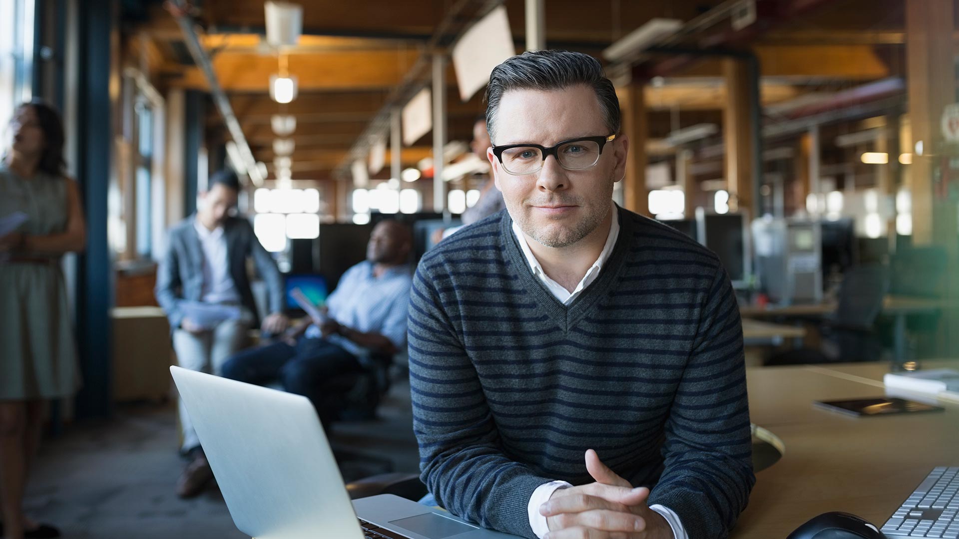 man sitting at a desk with hands folded