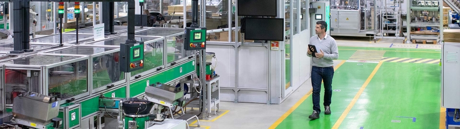 man walking through factory holding a tablet