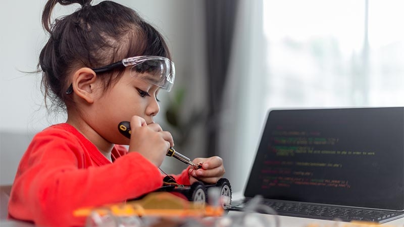 A child wearing safety goggles and holding a screwdriver