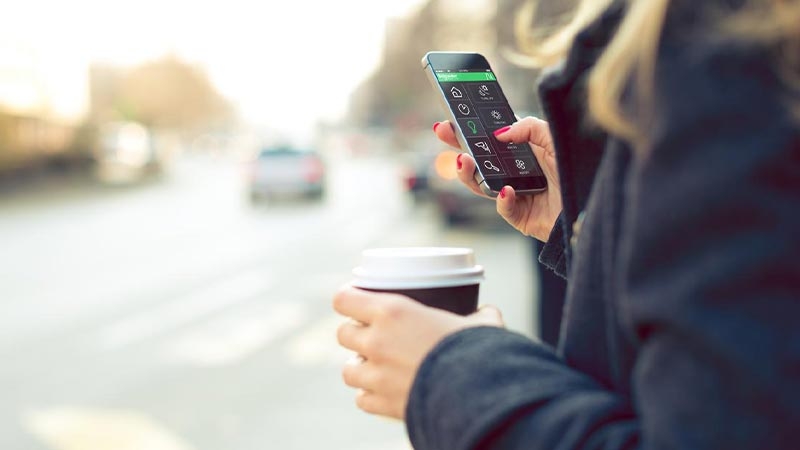 A person holding a phone and a cup of coffee