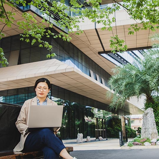 A person sitting on a bench with a computer