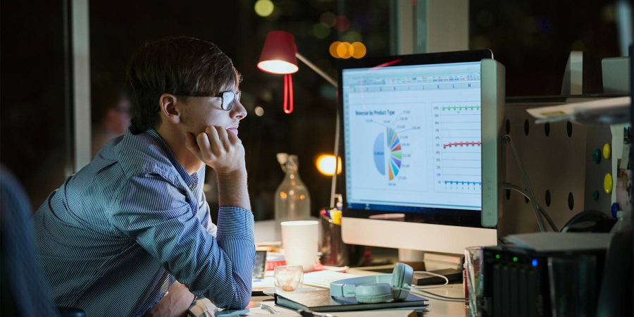 man looking at computer screen with stats chart