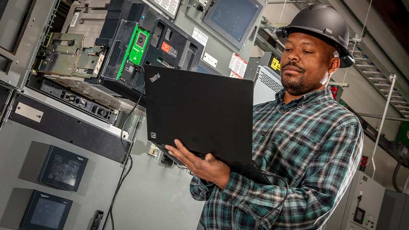 A person in a hard hat holding a computer